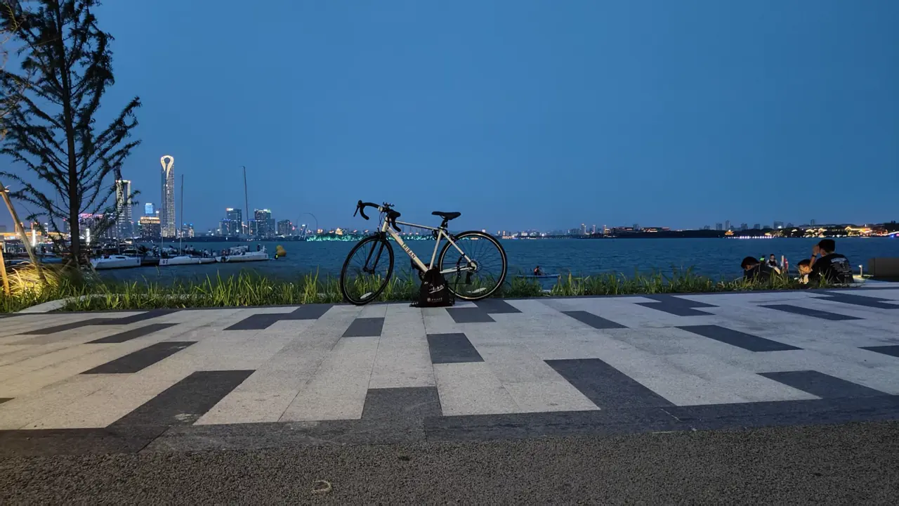 A bicycle beside a lake and city skyline at night
